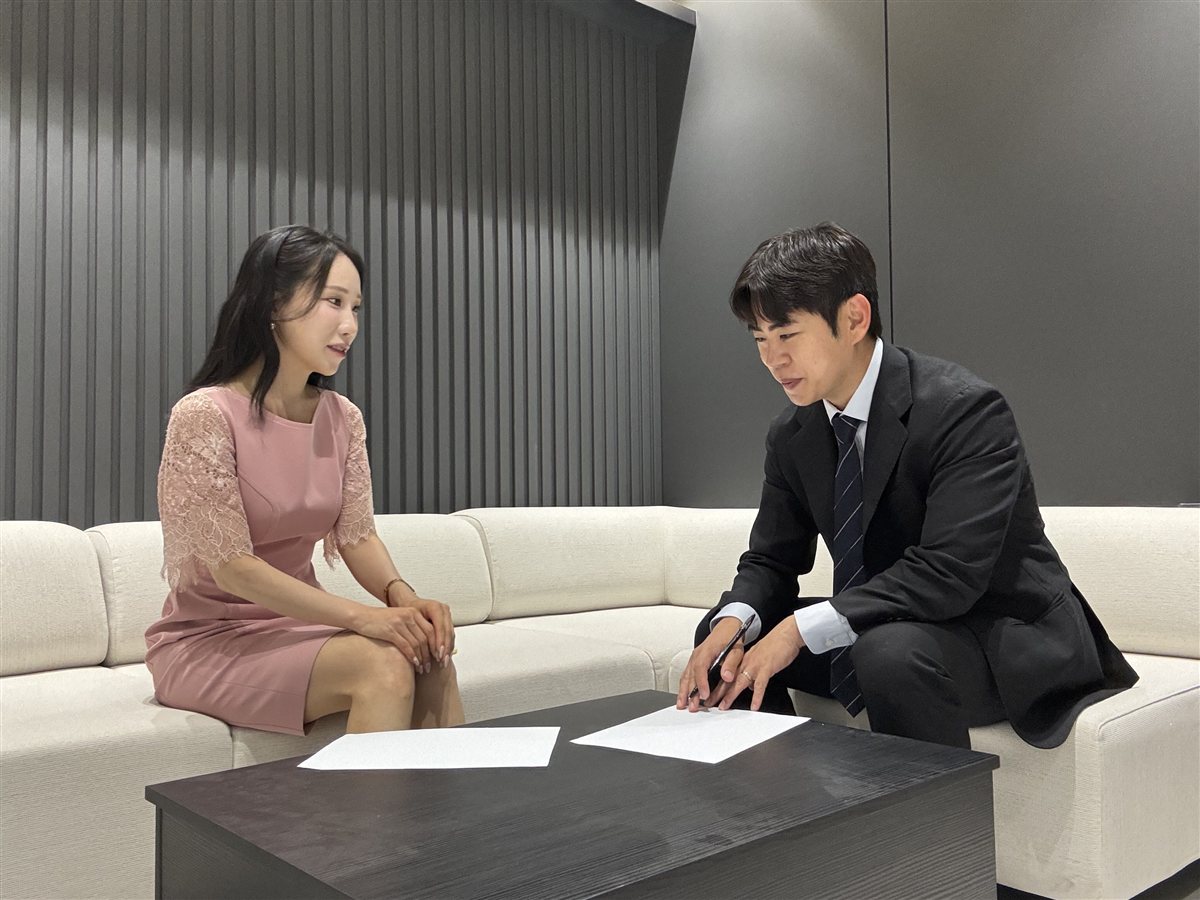 상담 테이블의 서류를 짚으며 의뢰인과 대화하는 최동준 변호사